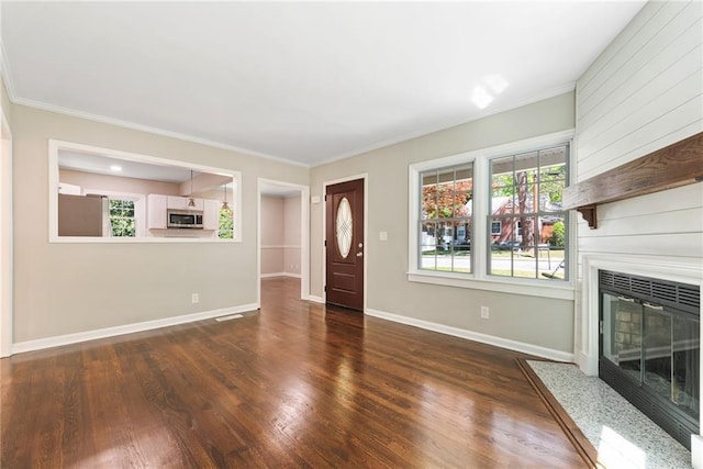 unfurnished living room with ornamental molding, a fireplace, baseboards, and wood finished floors