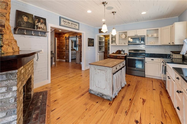 kitchen with butcher block countertops, appliances with stainless steel finishes, decorative light fixtures, light wood-type flooring, and open shelves