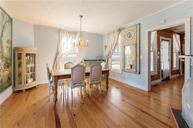 dining room featuring visible vents, hardwood / wood-style floors, an inviting chandelier, ornamental molding, and baseboards