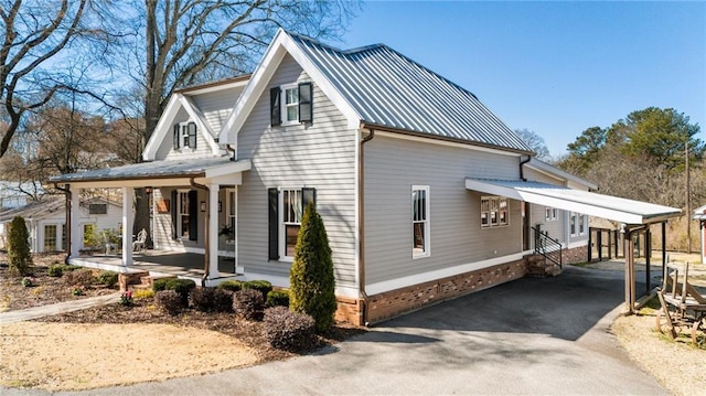 view of property exterior with a porch, entry steps, metal roof, and aphalt driveway