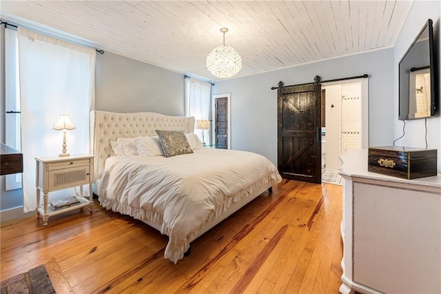 bedroom with wood ceiling, crown molding, light wood-style flooring, and a barn door