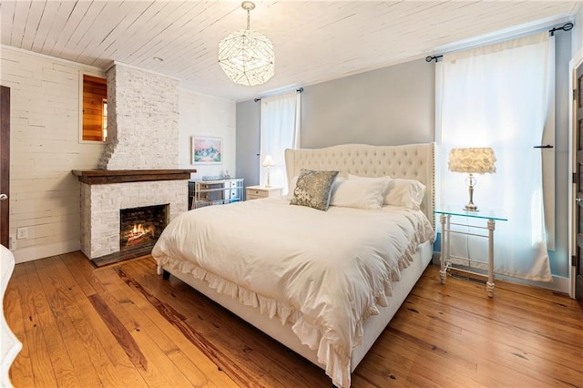 bedroom with wooden ceiling, hardwood / wood-style flooring, and a fireplace