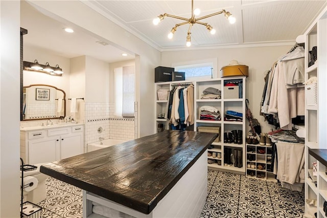 walk in closet with tile patterned flooring, a sink, and an inviting chandelier