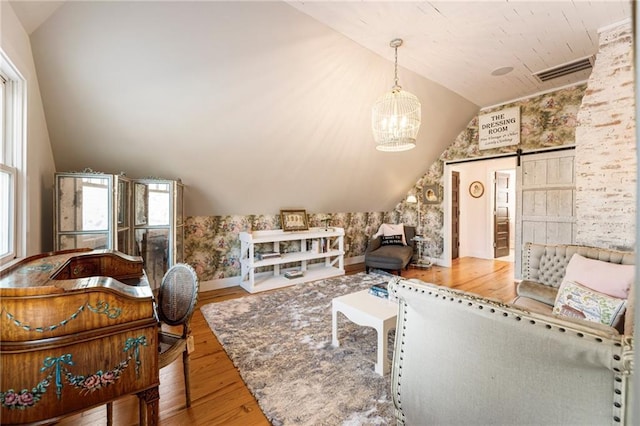 living area featuring lofted ceiling, a barn door, visible vents, and hardwood / wood-style floors