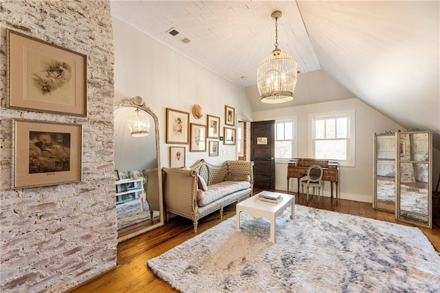 living area with lofted ceiling, wood finished floors, visible vents, and an inviting chandelier