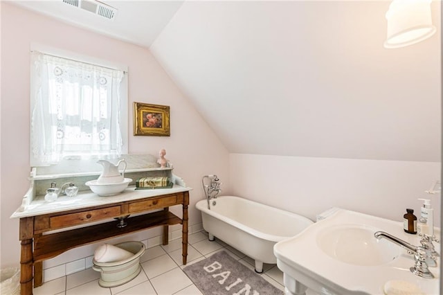 full bathroom featuring visible vents, vaulted ceiling, vanity, tile patterned flooring, and a freestanding tub