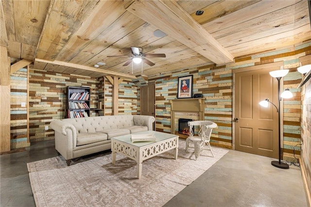 living area featuring a warm lit fireplace, wooden walls, a ceiling fan, wood ceiling, and concrete floors