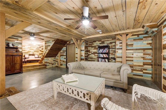 living area with finished concrete floors, wood ceiling, wood walls, and a ceiling fan