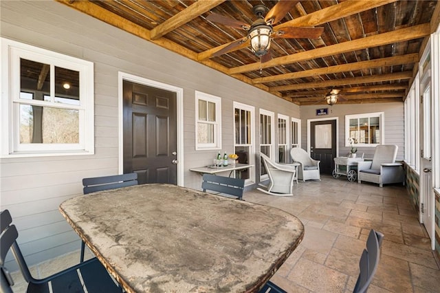 sunroom featuring beam ceiling, wood ceiling, and a ceiling fan