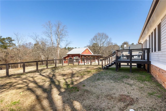 view of yard featuring a deck, stairway, and fence