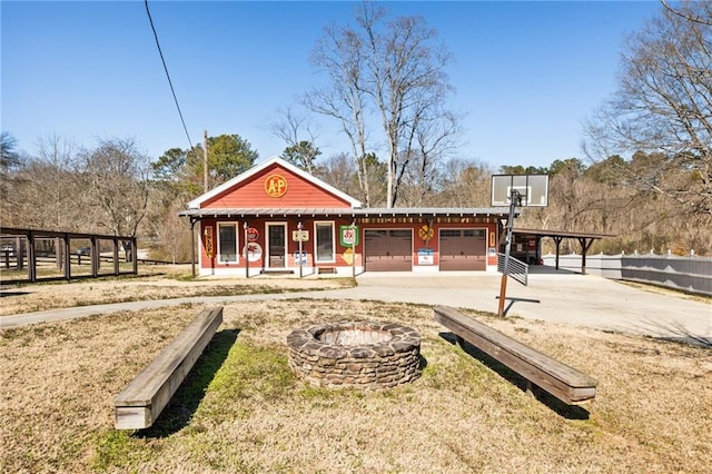 view of front of property with an outdoor fire pit, driveway, an attached garage, and fence