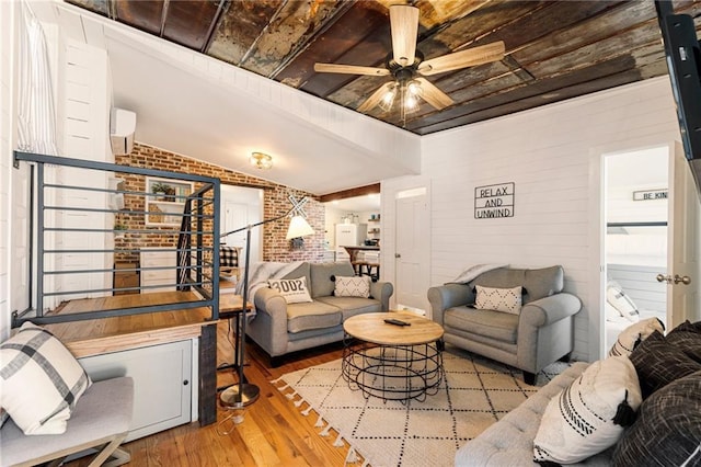 living room with a ceiling fan, lofted ceiling, brick wall, wood finished floors, and a wall mounted AC