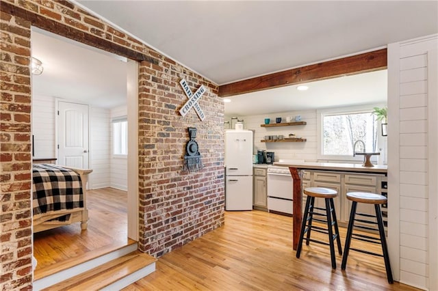 kitchen with white appliances, brick wall, and plenty of natural light