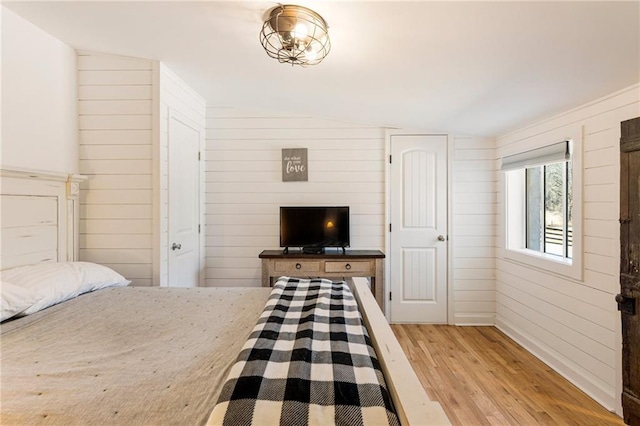 bedroom with wood walls and light wood-style flooring