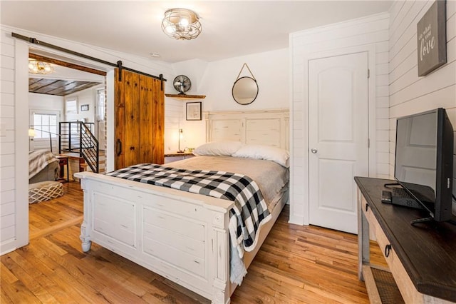 bedroom with a barn door and light wood-style floors