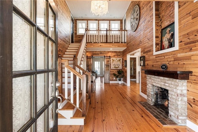 foyer featuring a barn door, wood finished floors, stairs, wood walls, and a brick fireplace