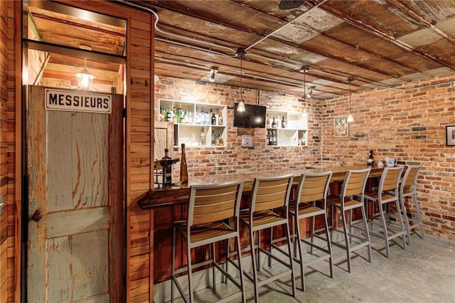 bar with brick wall, a dry bar, and unfinished concrete floors