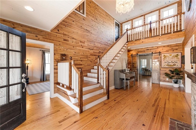 entrance foyer with wood walls, stairway, and a barn door