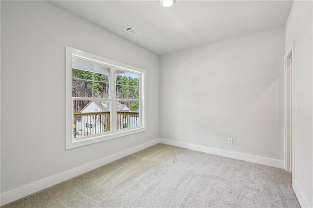 spare room with carpet flooring, visible vents, and baseboards