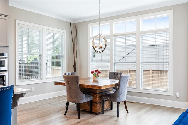 dining room with baseboards, ornamental molding, light wood-type flooring, and a chandelier