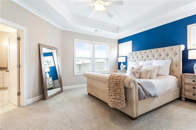 bedroom featuring ceiling fan, a tray ceiling, light colored carpet, and baseboards