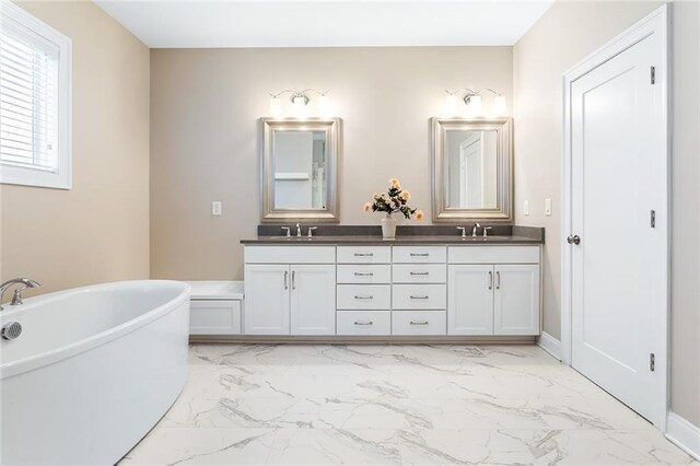 bathroom featuring a sink, a freestanding tub, double vanity, and marble finish floor