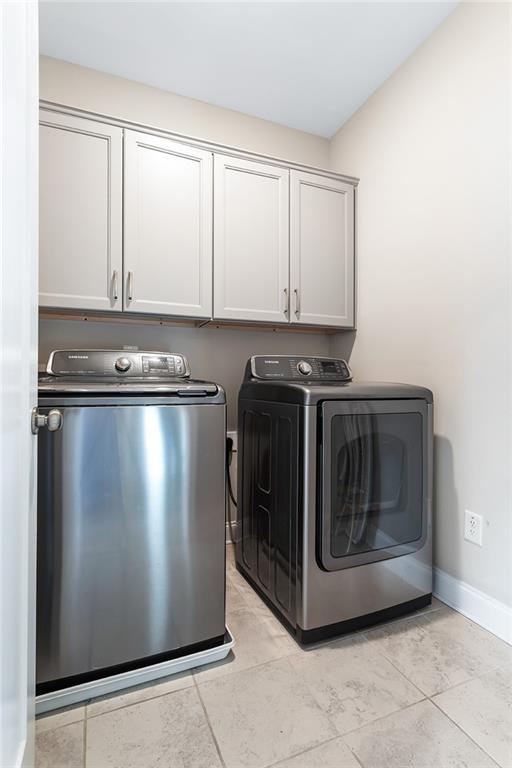 clothes washing area with baseboards, cabinet space, and washing machine and dryer