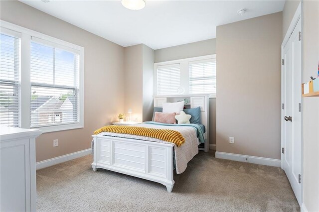 bedroom with light colored carpet, baseboards, and multiple windows