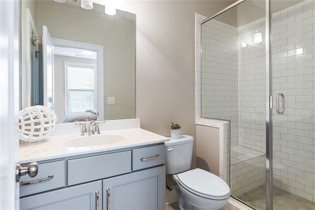 bathroom featuring vanity, connected bathroom, toilet, and a shower stall