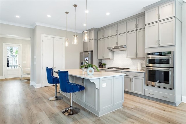 kitchen featuring backsplash, stainless steel appliances, gray cabinetry, light countertops, and under cabinet range hood
