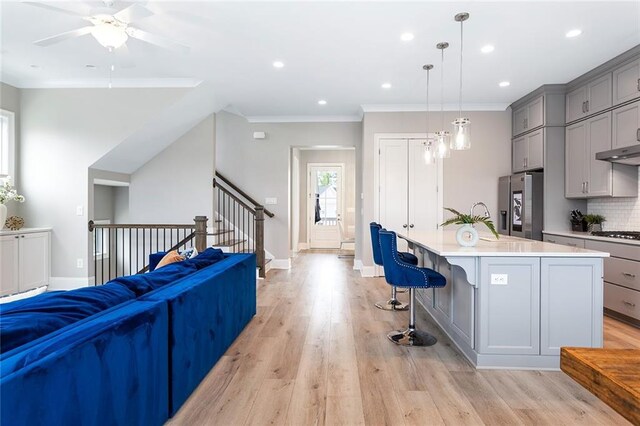 kitchen with stainless steel fridge, light countertops, gas stovetop, light wood finished floors, and gray cabinetry
