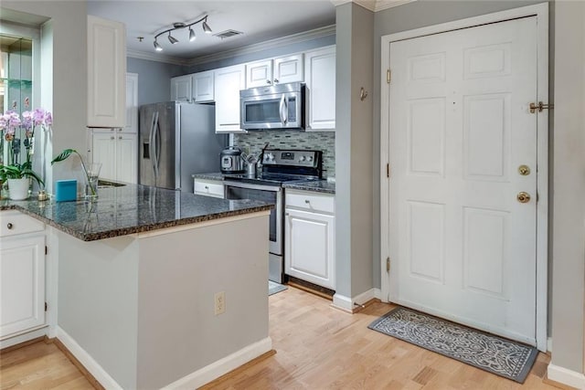 kitchen with appliances with stainless steel finishes, crown molding, white cabinetry, light wood-style flooring, and a peninsula