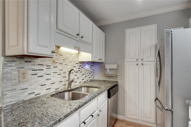 kitchen featuring appliances with stainless steel finishes, a sink, white cabinetry, stone countertops, and tasteful backsplash