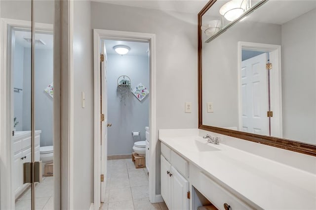 bathroom with toilet, vanity, tile patterned floors, and baseboards