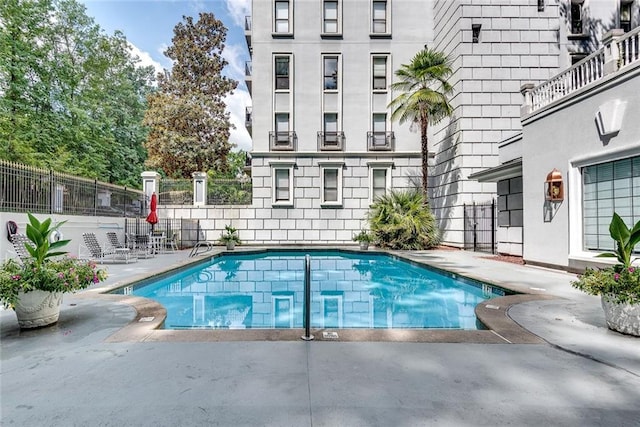 community pool with fence and a patio