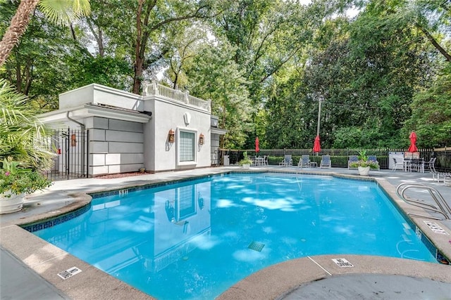 community pool featuring fence, a patio area, and view of scattered trees