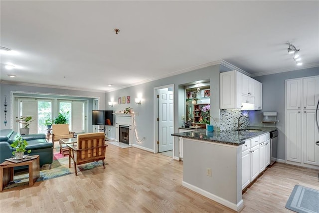 kitchen with dark stone counters, stainless steel dishwasher, light wood-style floors, white cabinets, and ornamental molding