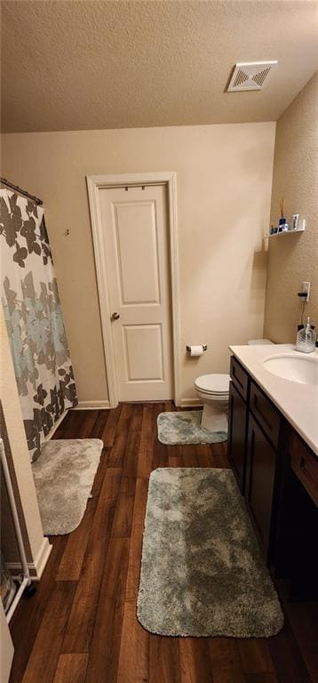 bathroom featuring vanity, a textured ceiling, wood-type flooring, and toilet