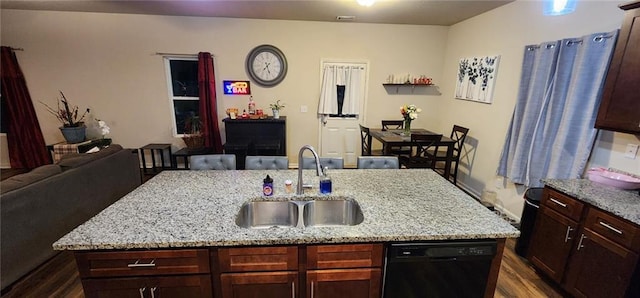 kitchen featuring dark hardwood / wood-style floors, black dishwasher, sink, a kitchen island with sink, and light stone countertops