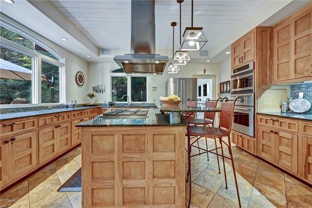 kitchen with a kitchen island, island range hood, a kitchen breakfast bar, pendant lighting, and dark stone countertops