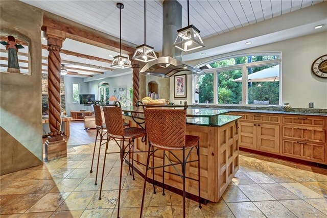 kitchen with beamed ceiling, a kitchen breakfast bar, pendant lighting, and a healthy amount of sunlight