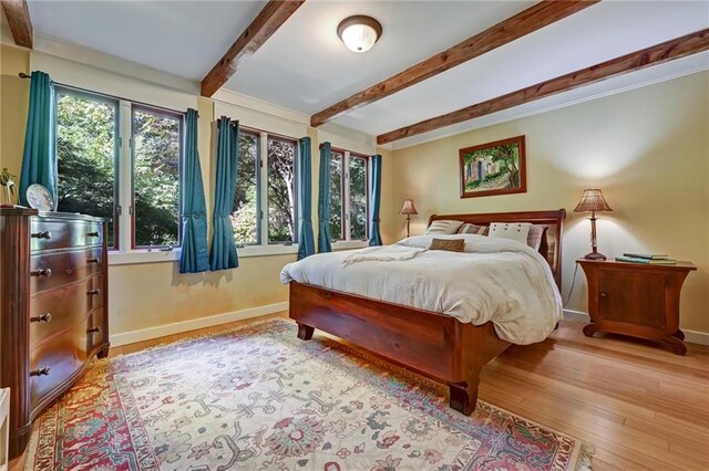 bedroom featuring light hardwood / wood-style floors and beamed ceiling