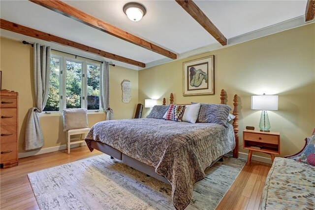 bedroom with beam ceiling and light hardwood / wood-style flooring