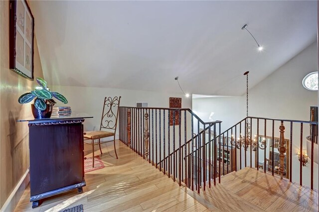 hall with lofted ceiling and light hardwood / wood-style flooring