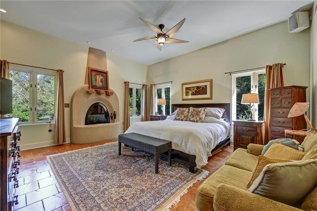 bedroom with a fireplace, multiple windows, and ceiling fan