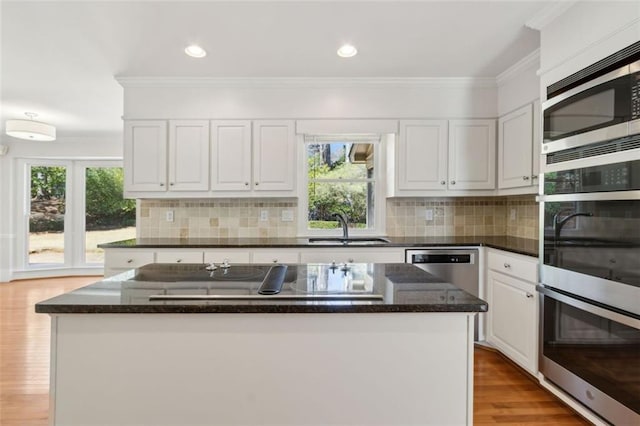 kitchen featuring ornamental molding, appliances with stainless steel finishes, white cabinets, and a sink