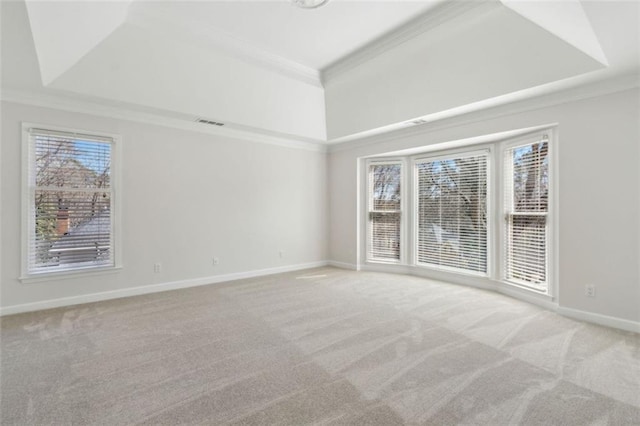 carpeted empty room featuring a tray ceiling, baseboards, visible vents, and ornamental molding