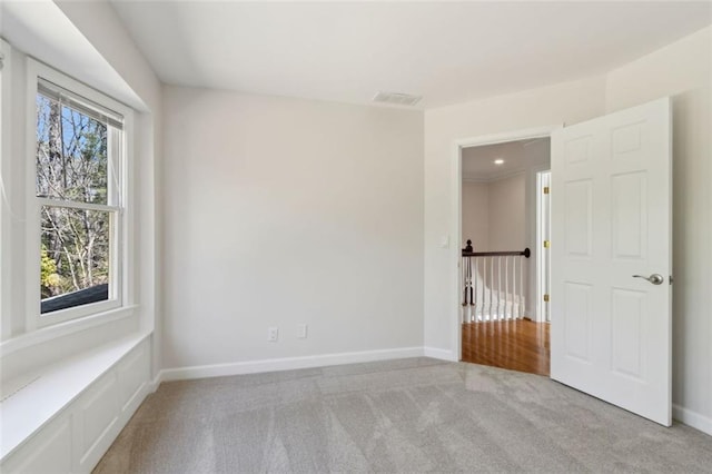 empty room featuring visible vents, baseboards, and light colored carpet