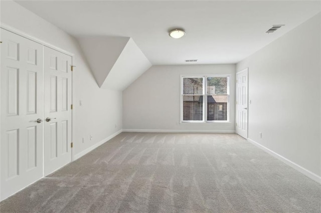 additional living space with baseboards, visible vents, and carpet floors