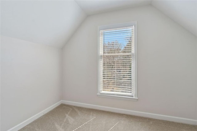 additional living space featuring light carpet, lofted ceiling, and a healthy amount of sunlight